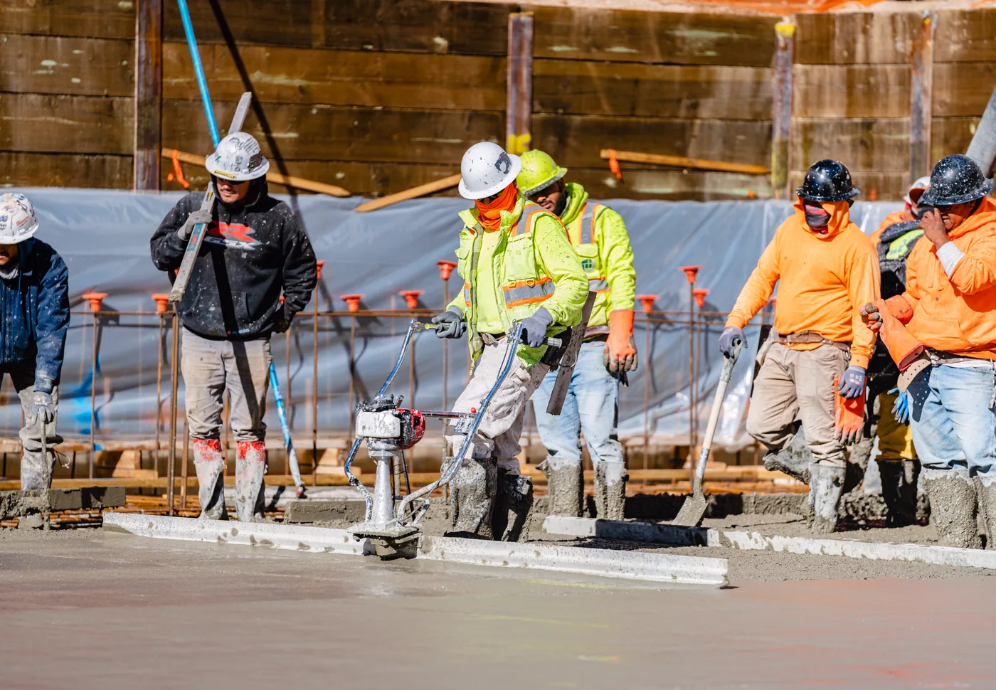 Concrete crew guiding a Tomahawk power screed across a fresh commercial pour