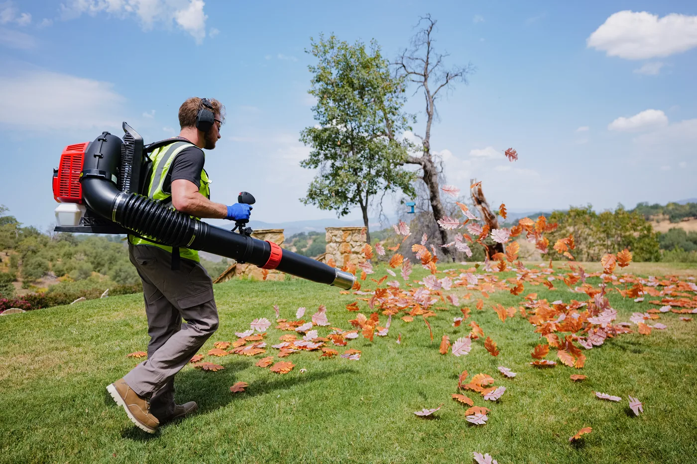 Landscaper clearing autumn leaves with a Tomahawk backpack blower