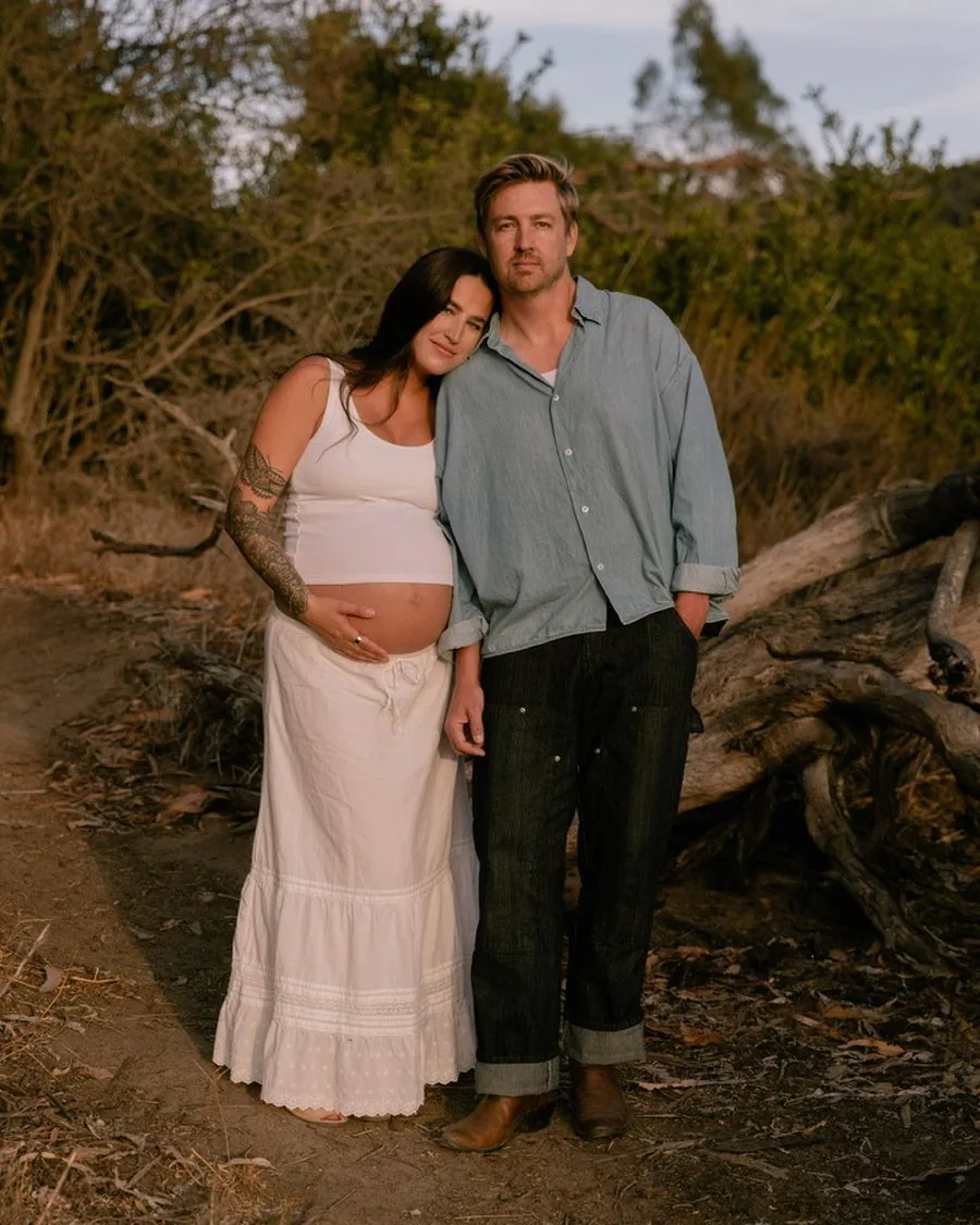 Lifestyle portrait of an expecting couple embracing outdoors