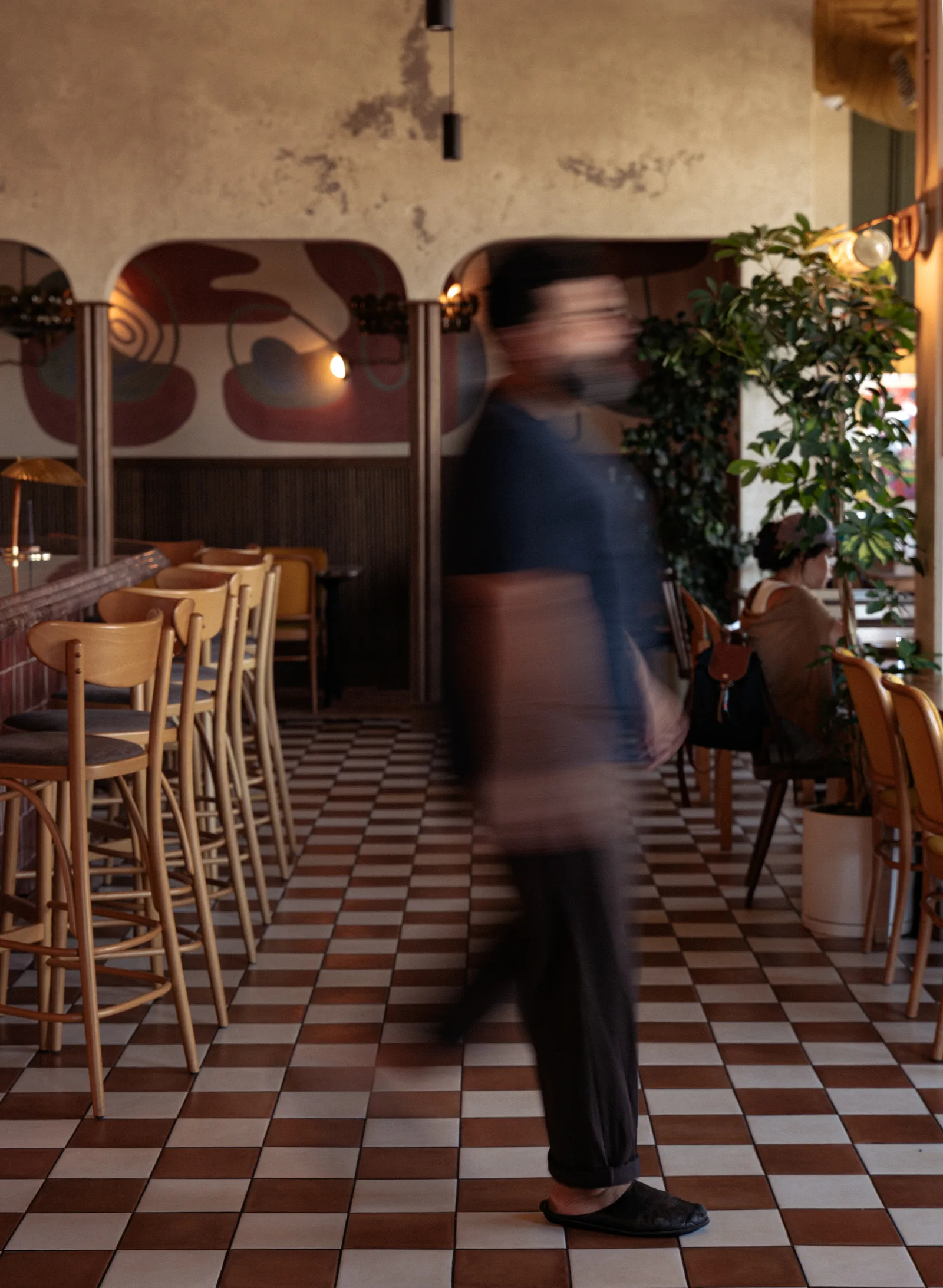 Server crossing the dining room over the brown and cream checkered tile floor