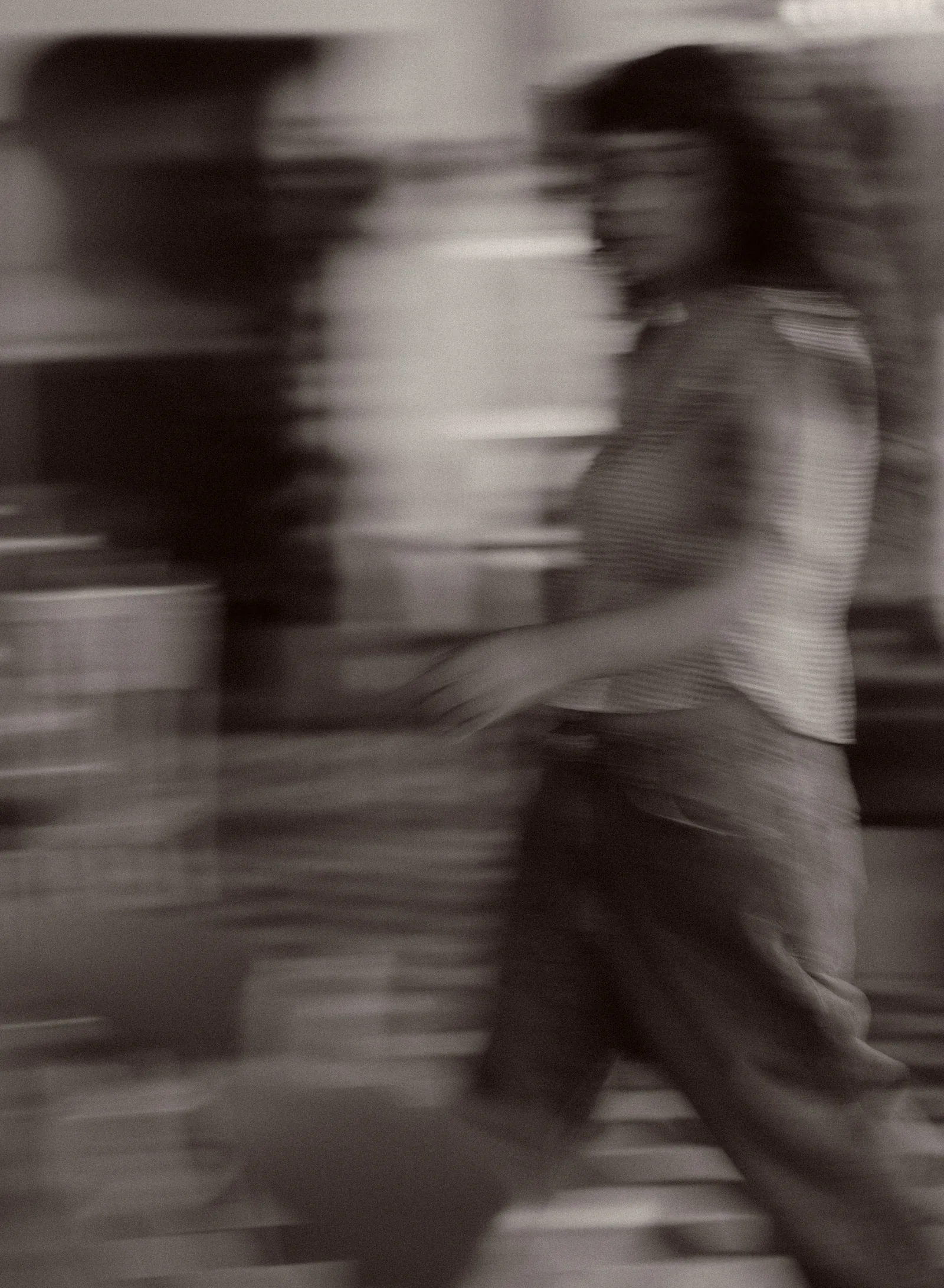 Black and white motion-blurred frame of a server walking through the room