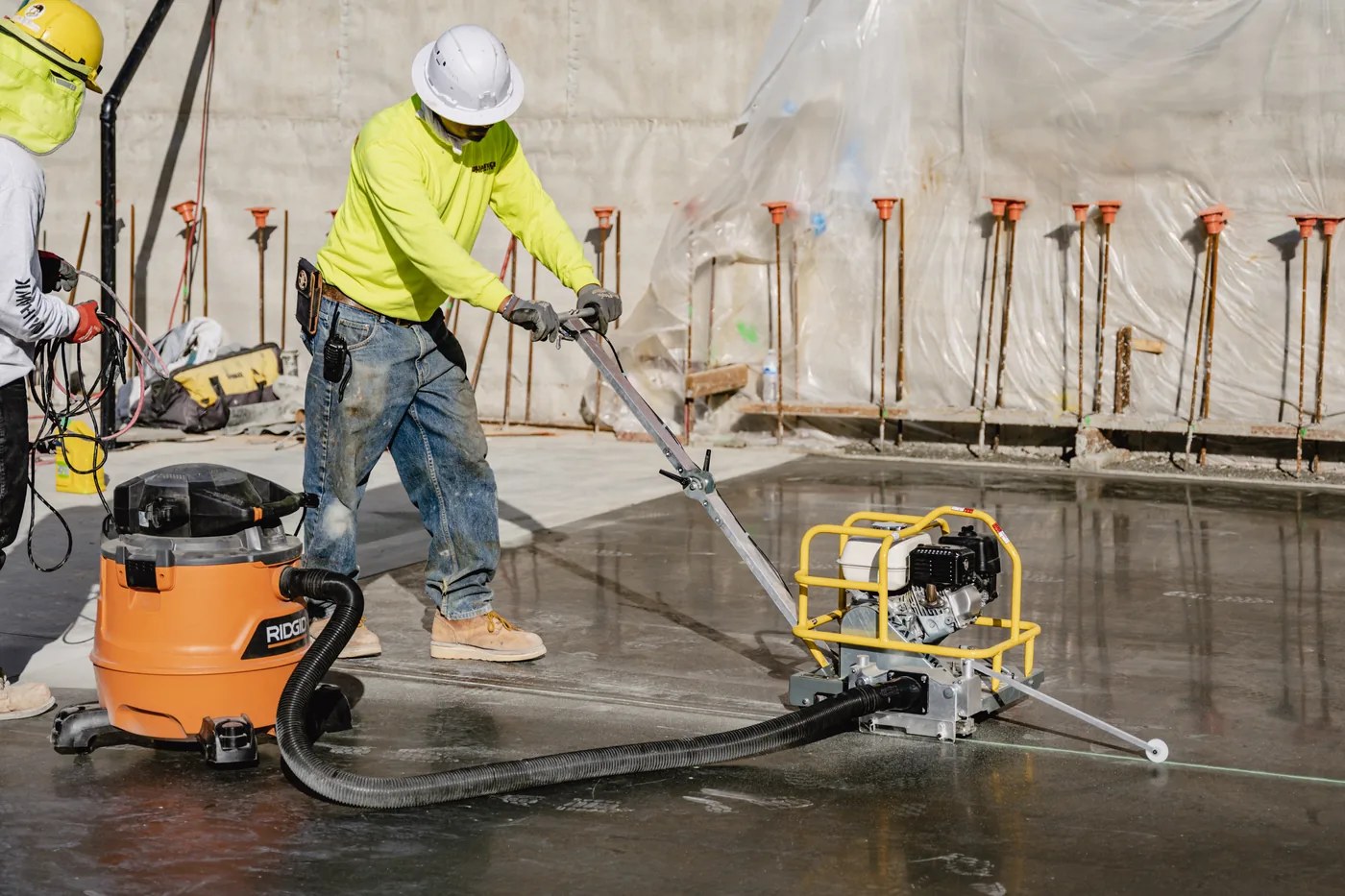 Operator grinding an interior concrete floor with dust extraction