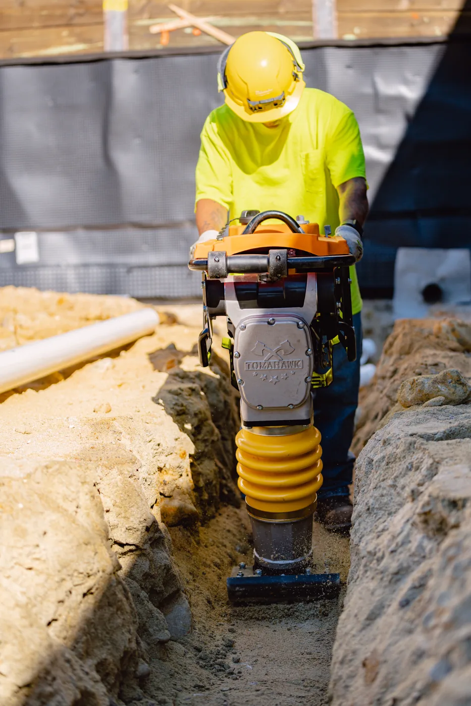 Overhead view of a worker compacting a trench with a Tomahawk rammer