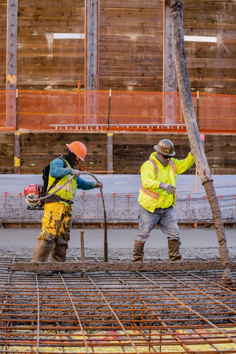 Two workers steadying formwork above a rebar grid