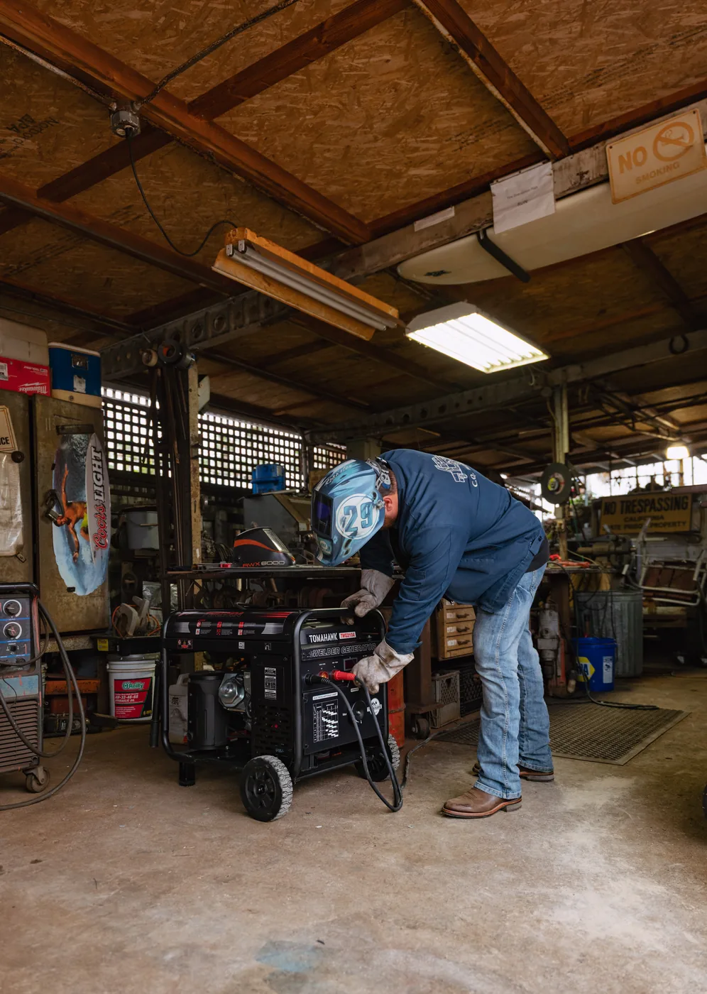 Welder at work in an open shop, generator running beside the bench
