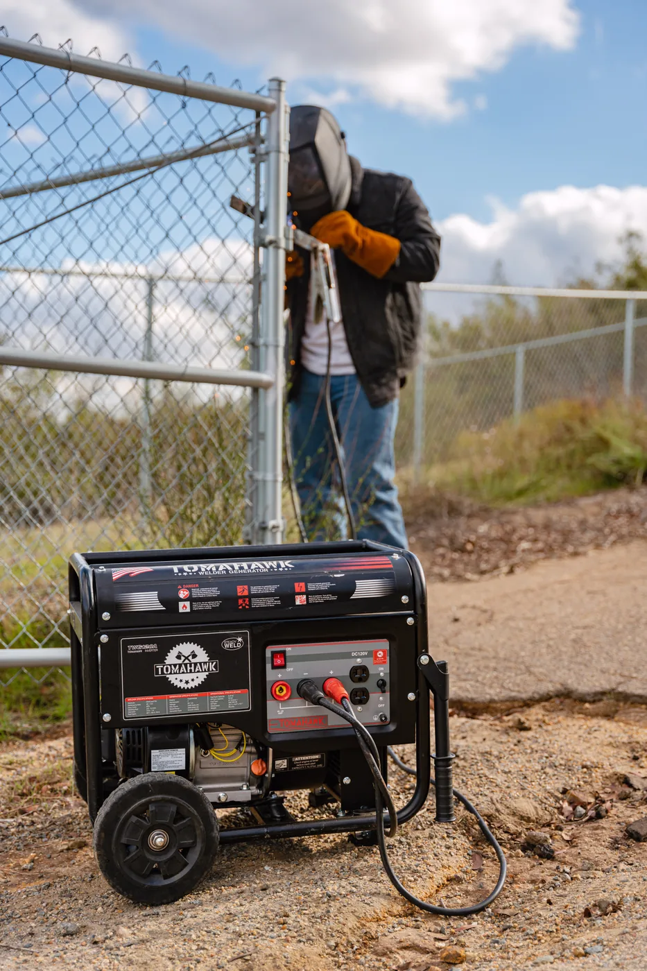 Welder resting against a fence post beside a running Tomahawk generator