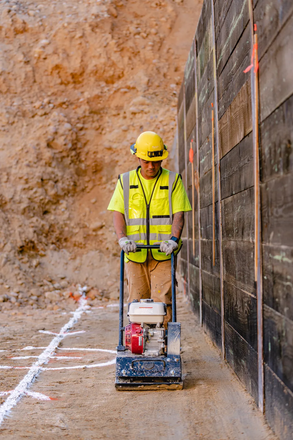 Worker pushing a concrete saw along a retaining wall