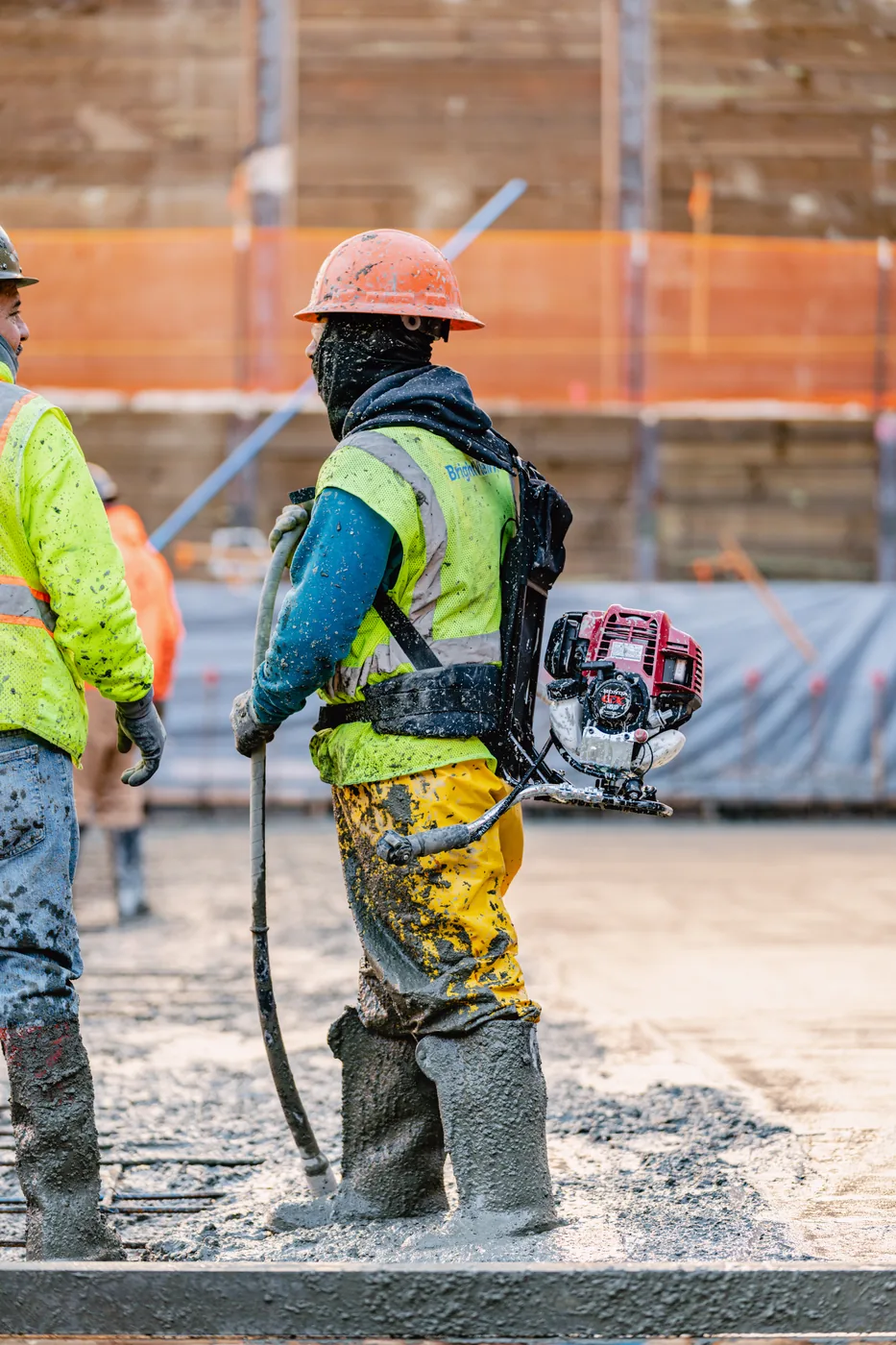 Worker running a concrete vibrator over a rebar mat
