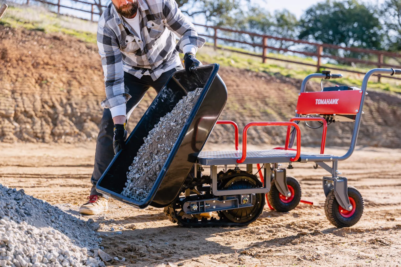 Worker tipping gravel from a Tomahawk powered wheelbarrow