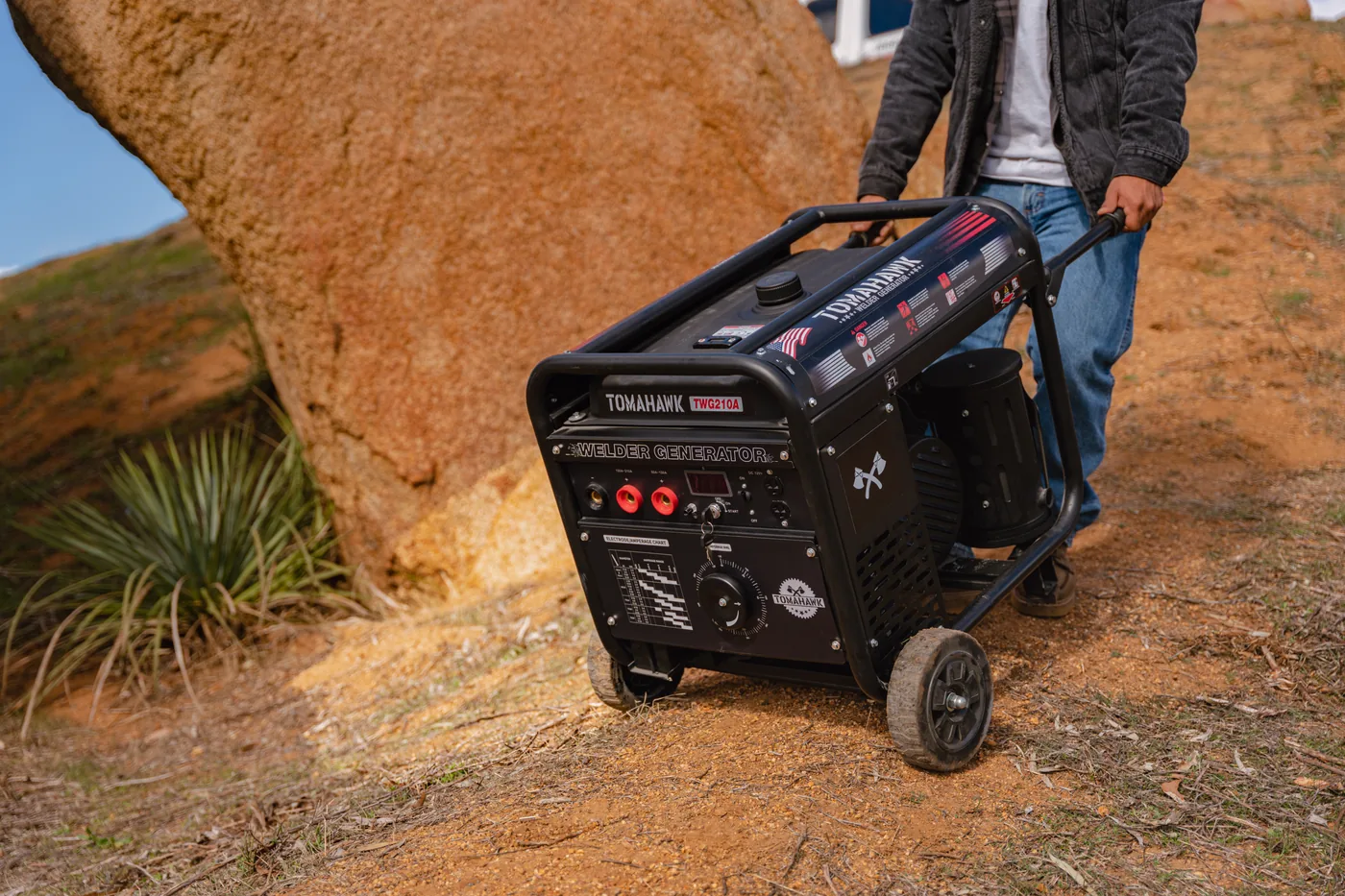 Worker towing a Tomahawk welder generator up a dirt slope